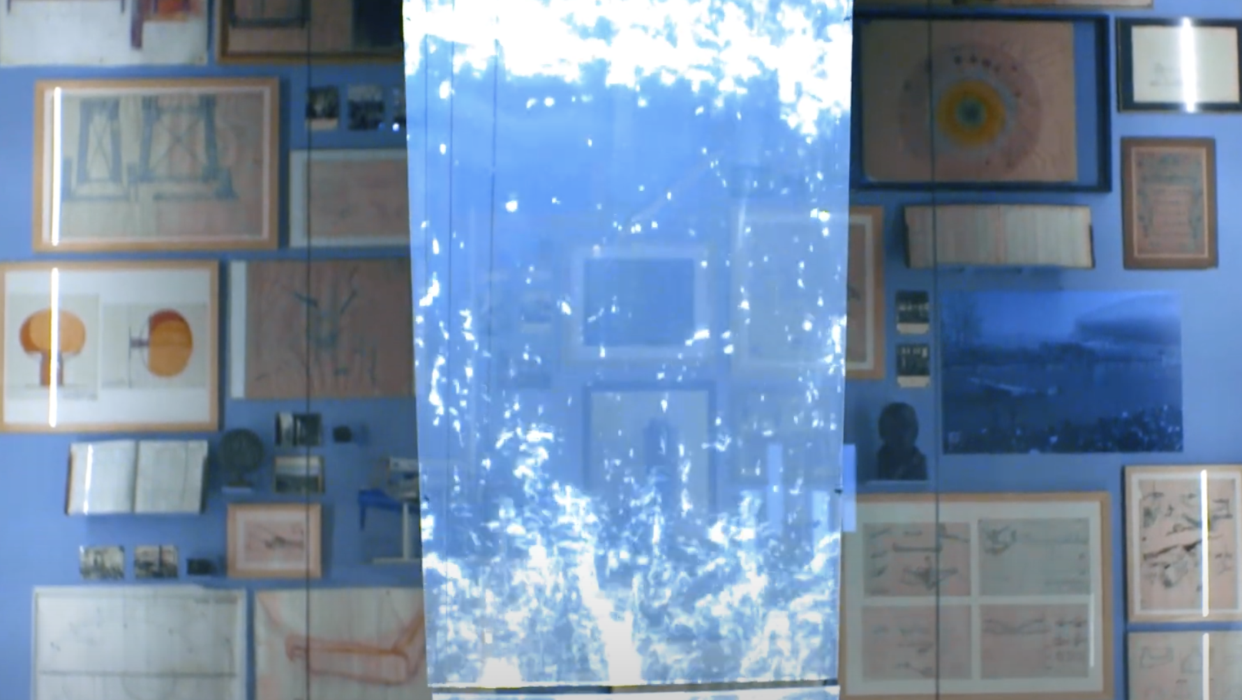 A collection of varied art pieces framed and hung on a blue wall, overlayed with a semi-transparent, water-textured blue r...