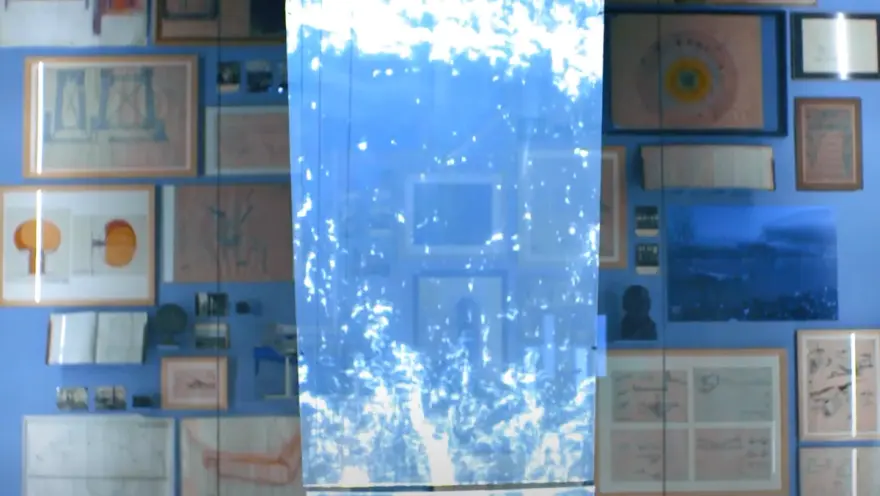 A collection of varied art pieces framed and hung on a blue wall, overlayed with a semi-transparent, water-textured blue r...