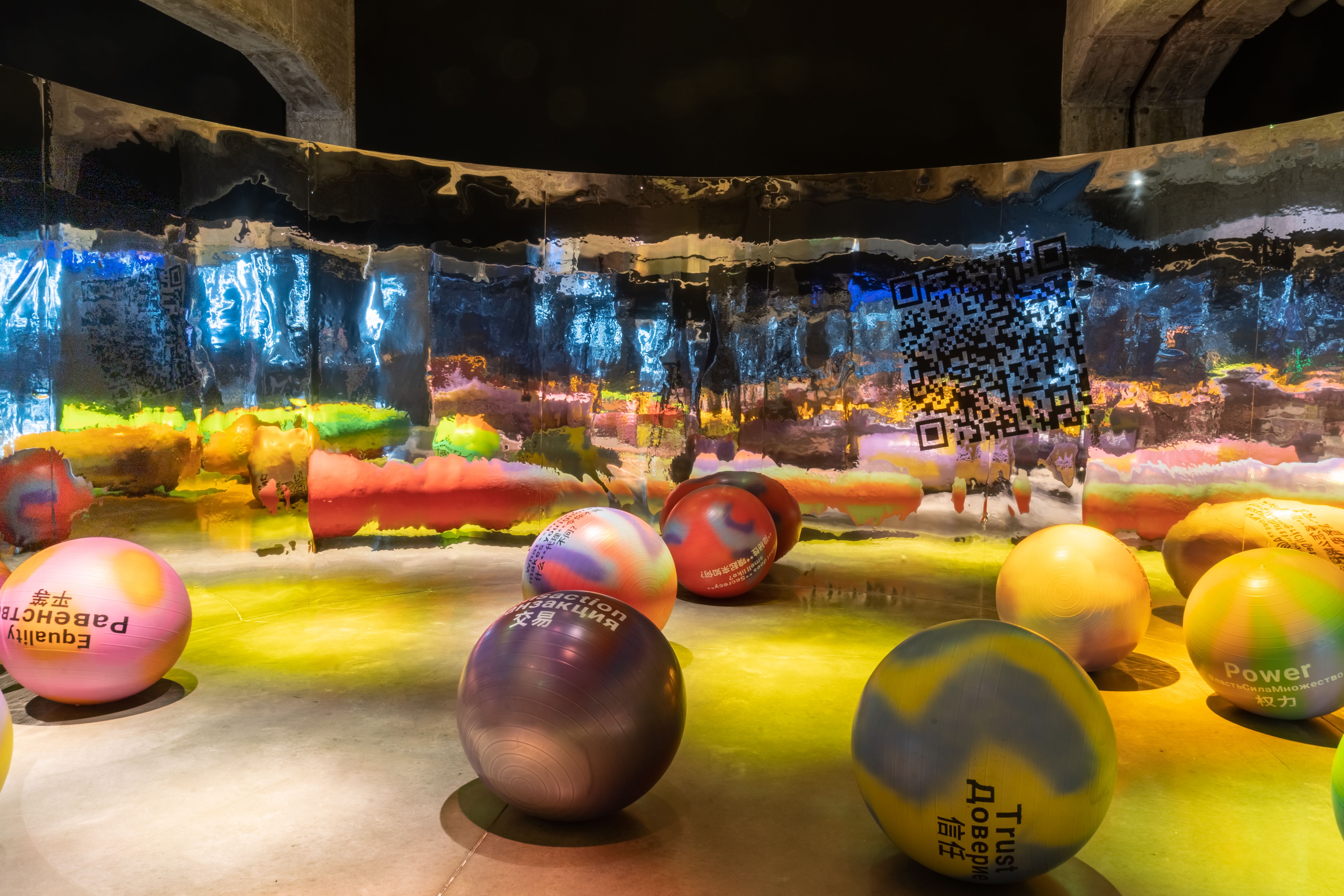 Artistic installation with colorful illuminated balls and reflective ceiling.