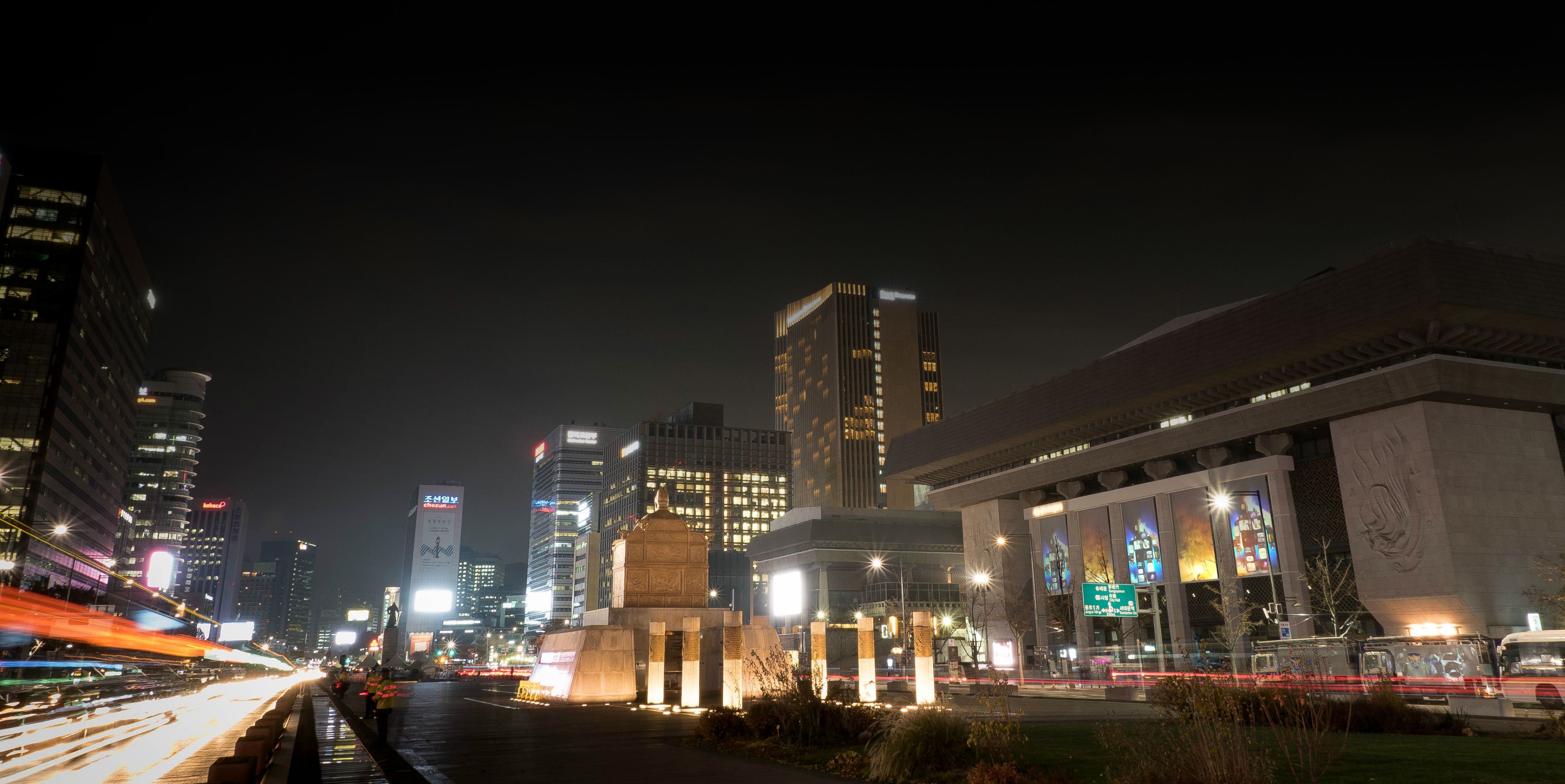 A time-lapse photograph capturing streaks of city lights against the night sky.