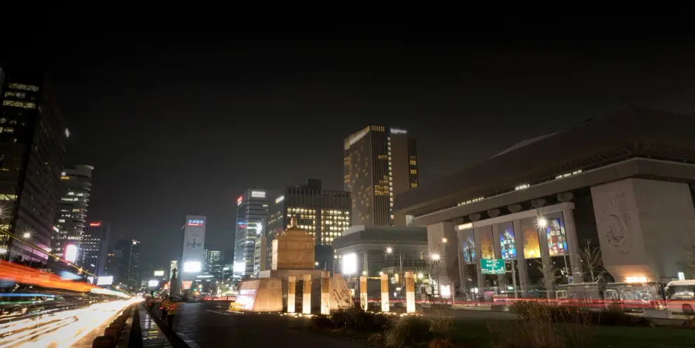 A time-lapse photograph capturing streaks of city lights against the night sky.