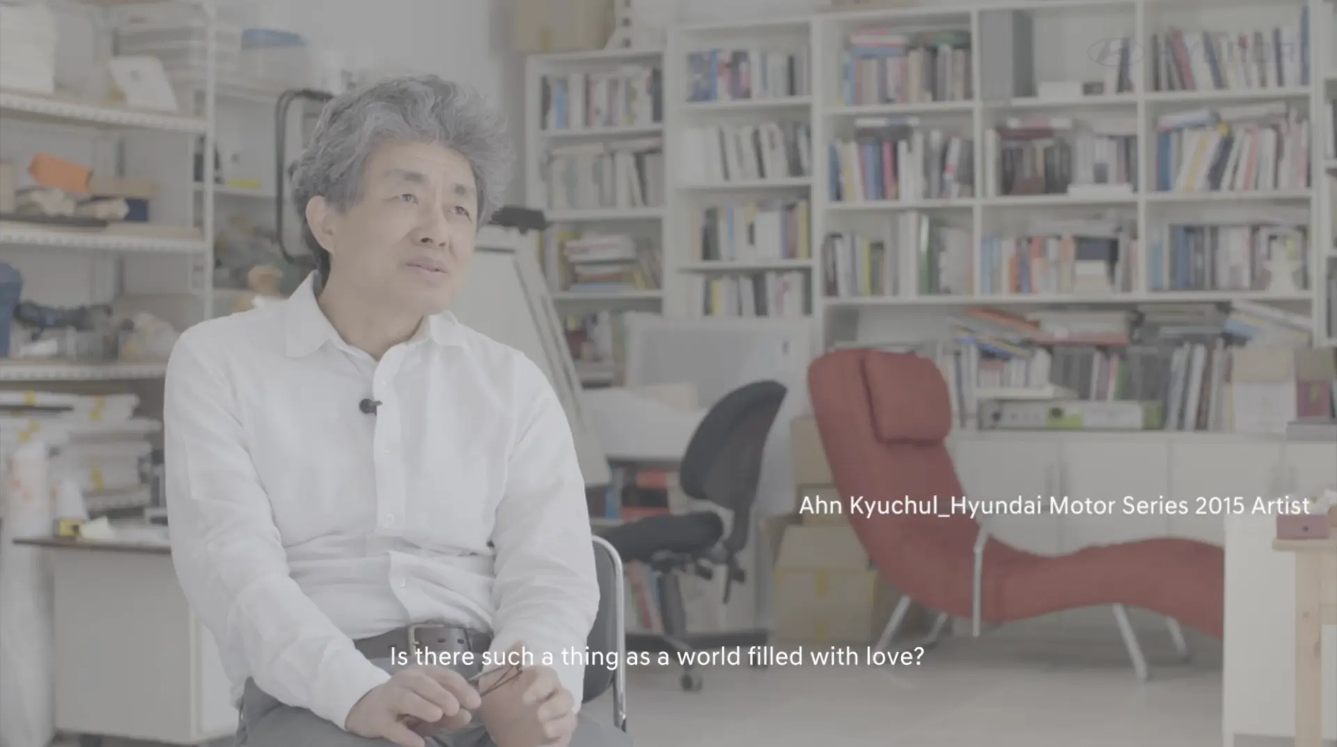 Ahn Kyuchul, the featured artist for Hyundai Motor Series 2015, is seen in an office setting with a bookshelf behind, gest...