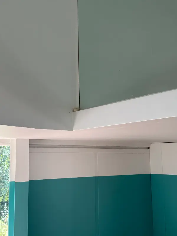 Corner view of teal and white walls in a minimalist space with soft natural lighting.