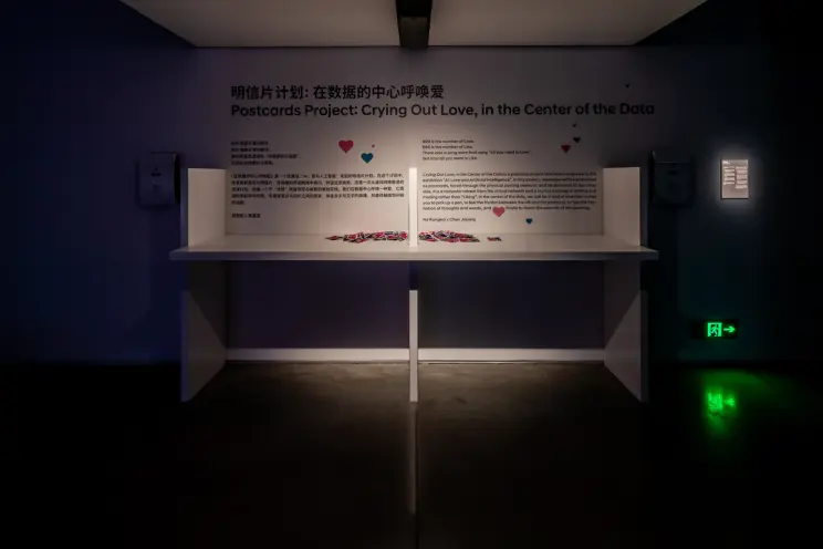 Exhibition space featuring a wall text and postcards project about data love.