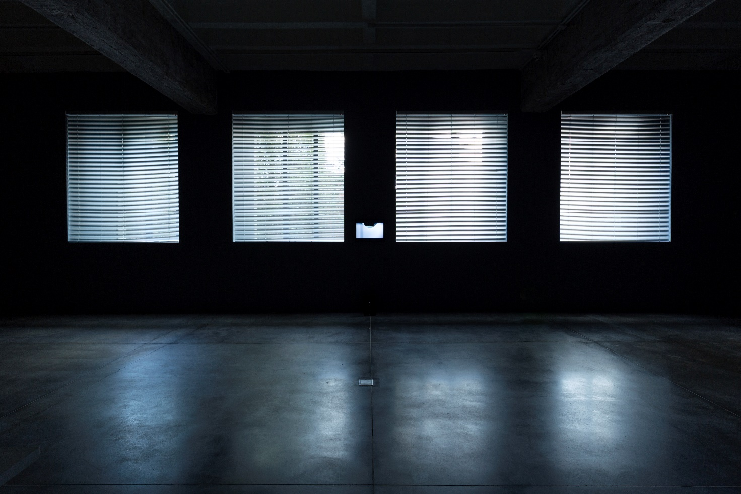 A room with four bright windows casting light on a polished concrete floor.