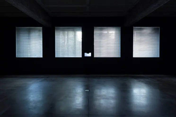 A room with four bright windows casting light on a polished concrete floor.
