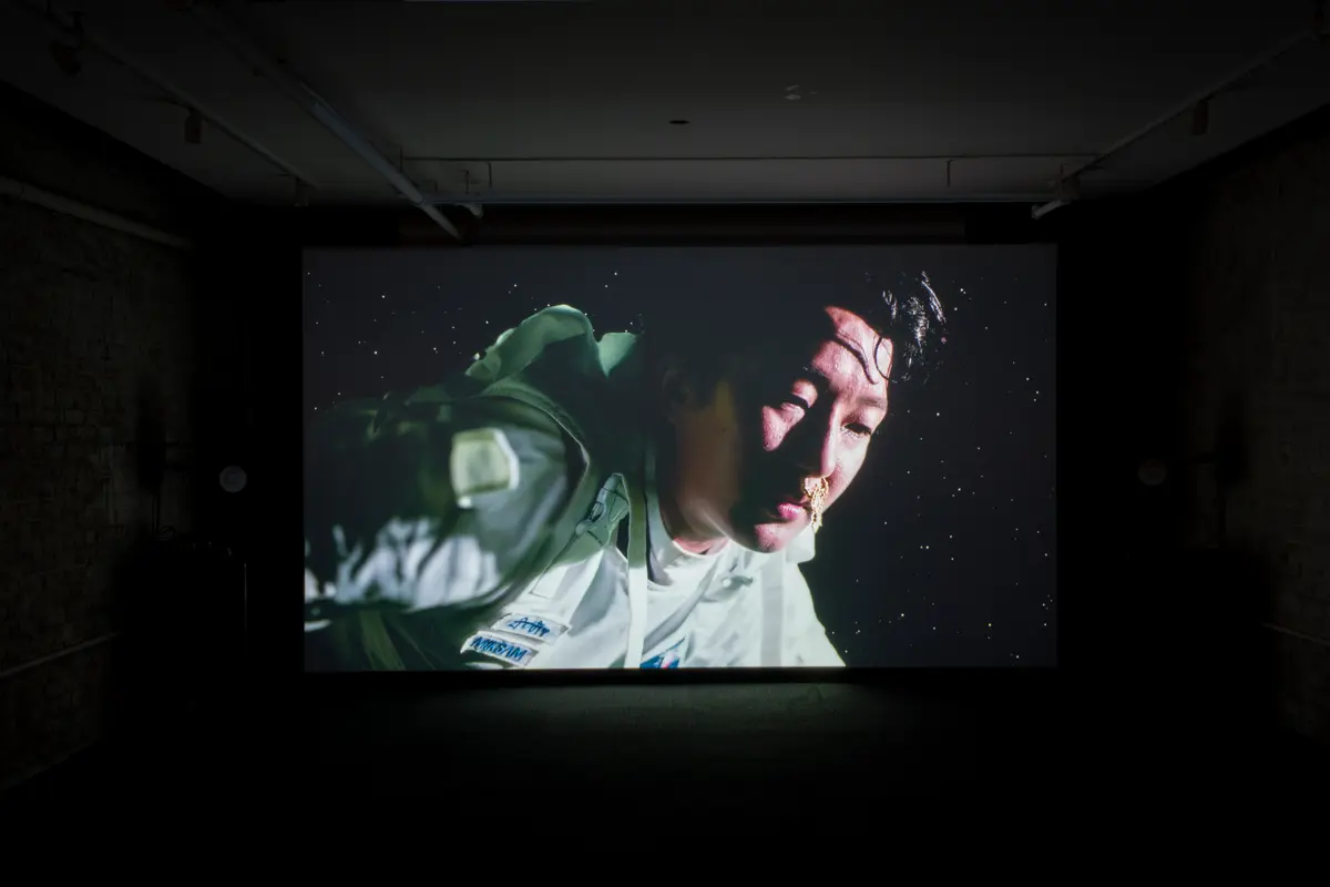 A movie projection in a room shows an astronaut floating in space.