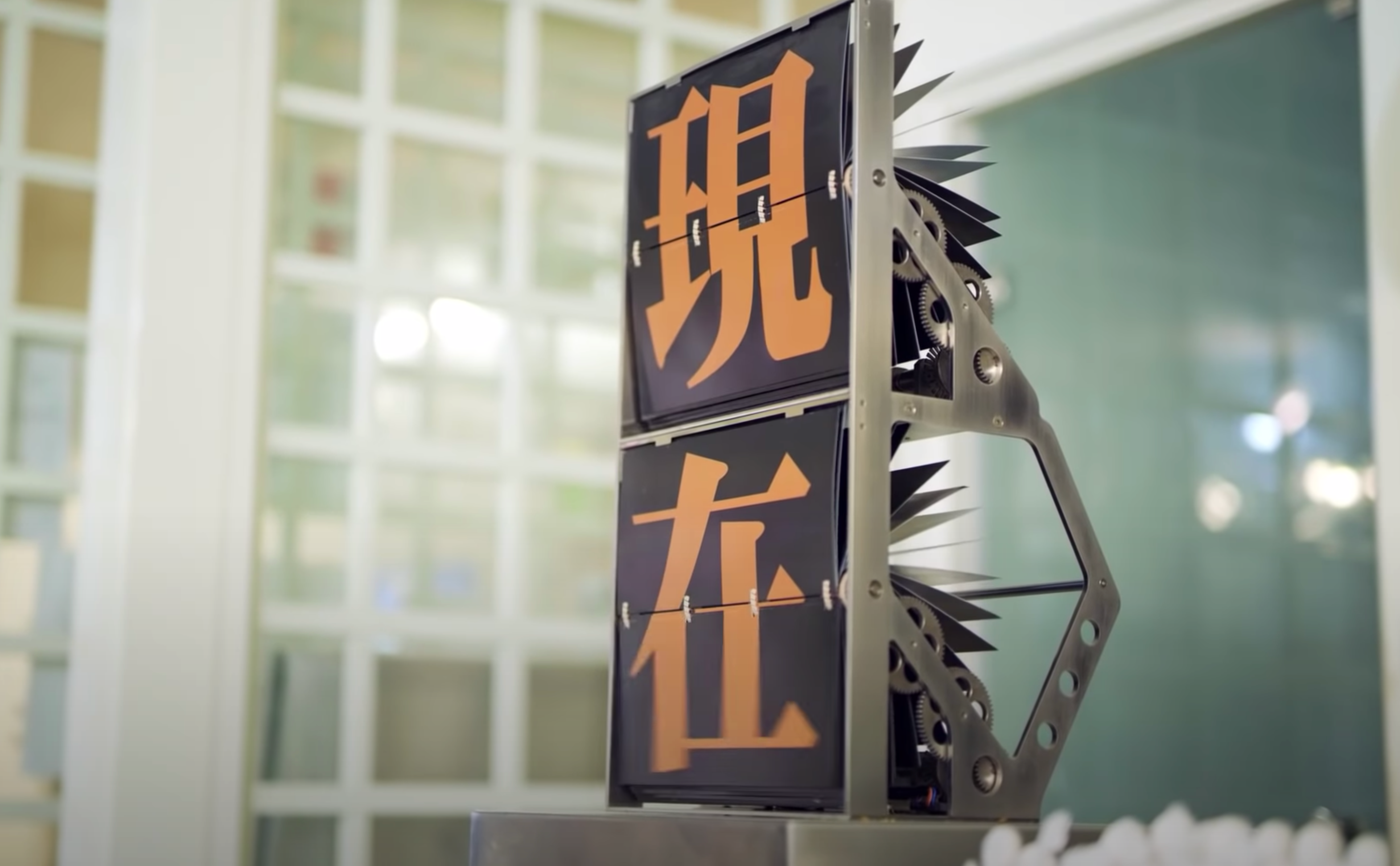 A flip counter machine displaying bright orange sinograms against a black backdrop, situated in a well-lit room with visib...