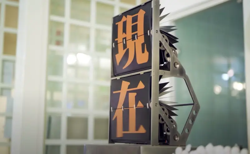 A flip counter machine displaying bright orange sinograms against a black backdrop, situated in a well-lit room with visib...