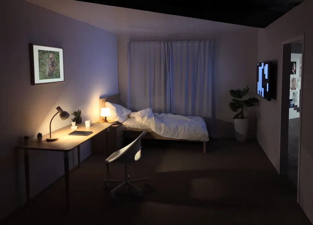 Dimly lit bedroom installation with digital art and ambient lighting.