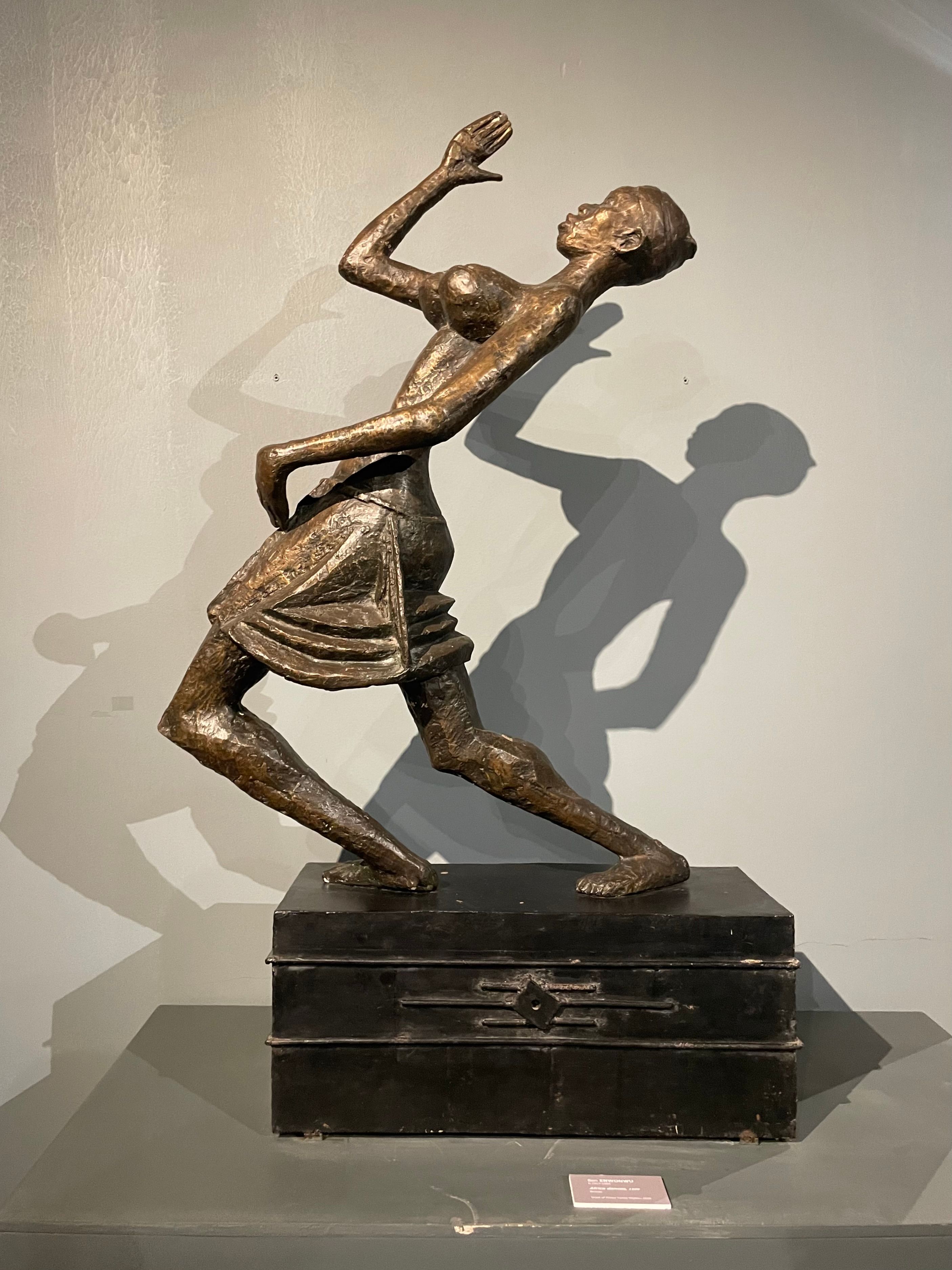 A dramatic bronze sculpture of a figure in motion on a black base.