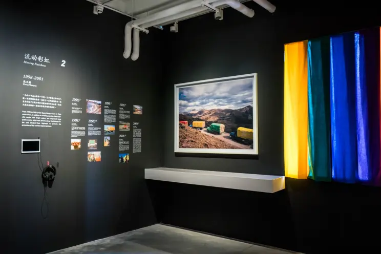 Exhibition space with colorful textile art and framed landscape photo.