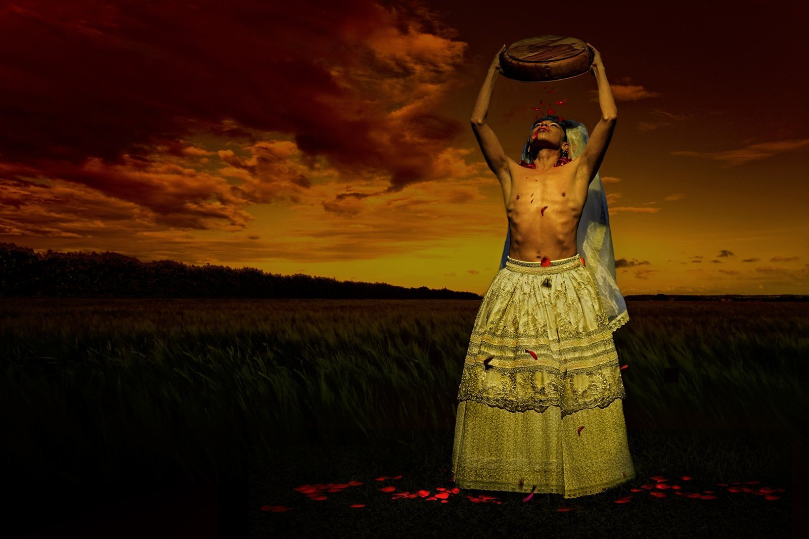 A person in vibrant traditional costume outside at twilight, raising a circular object high above their head.
