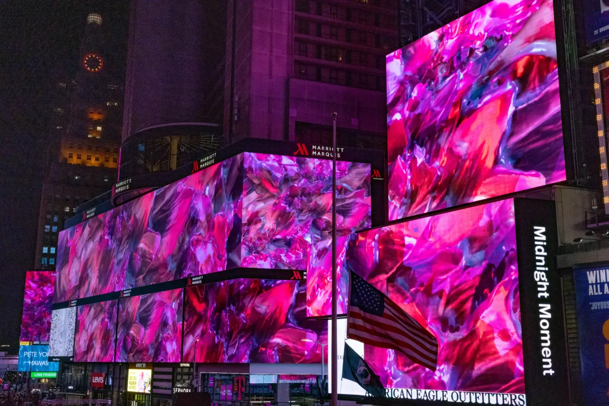 Abstract pink art displayed on multiple large advertisement screens, set against the backdrop of city buildings in Times Square.