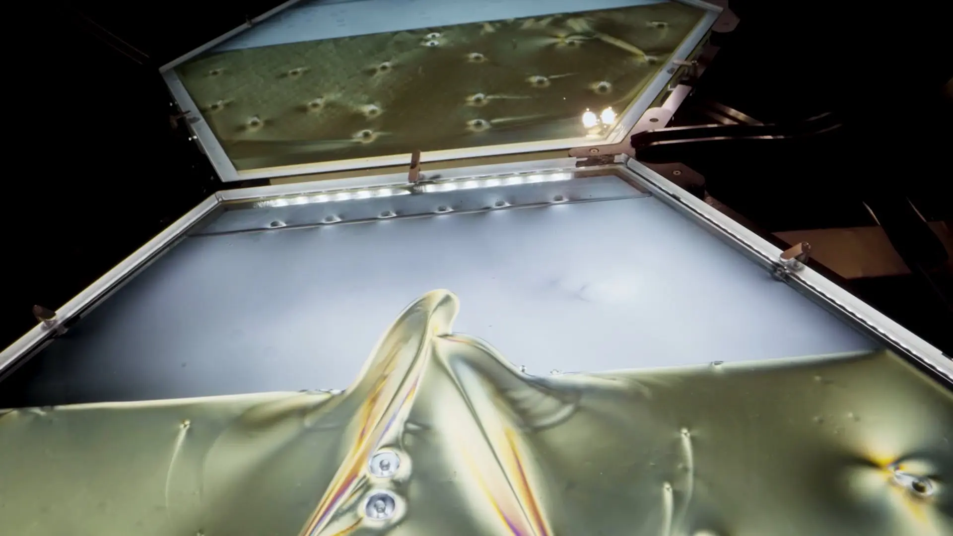 Close-up of a metallic structure with a reflective, glass-like surface creating distortions and colorful light refractions...