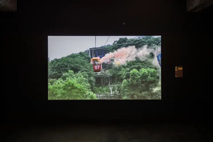 Exhibition space with video of a cable car over a green landscape.