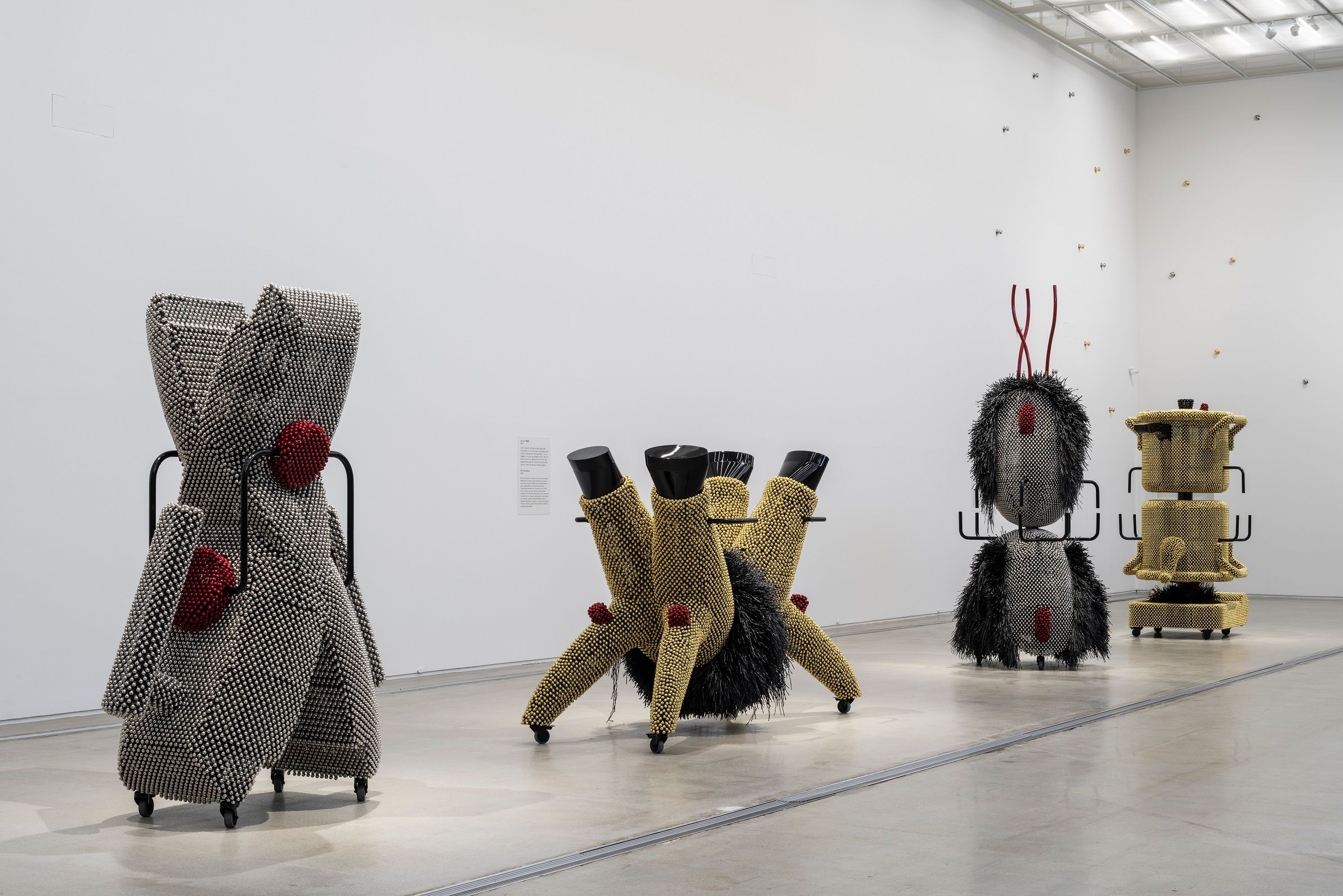 Art installation depicting oversized domestic items, adorned with golden and silver metal pins, conceptually evoking child...
