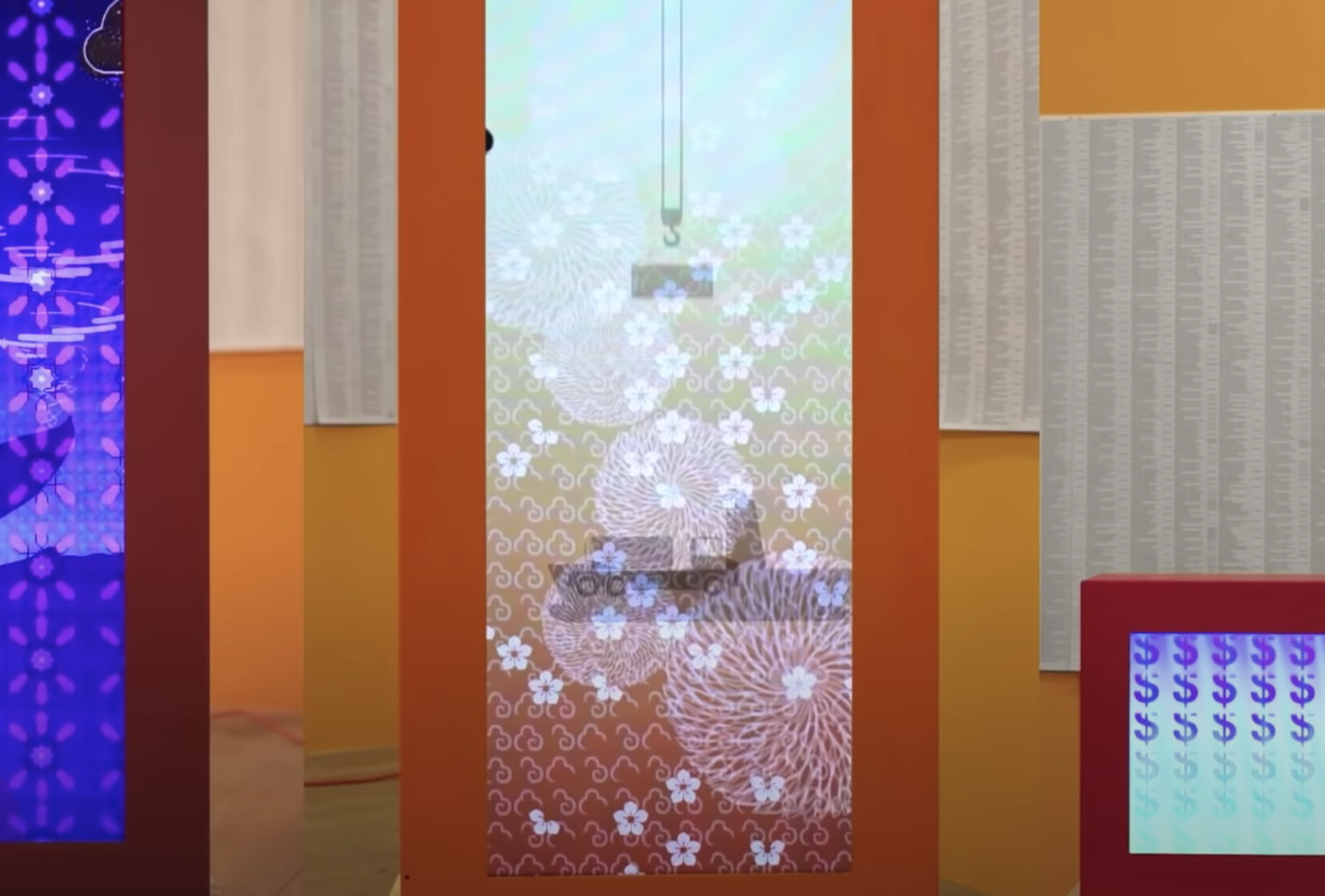 A vibrant collage featuring a variety of motifs adorns orange, yellow, and red walls. Materials with floral patterns, docu...