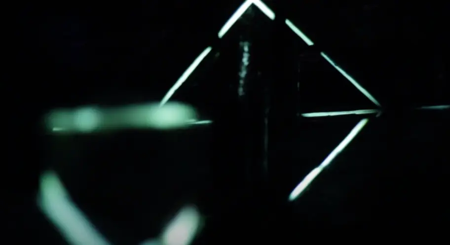 A dark background illuminated by hypnotic green neon light lines in a projection mapping display.