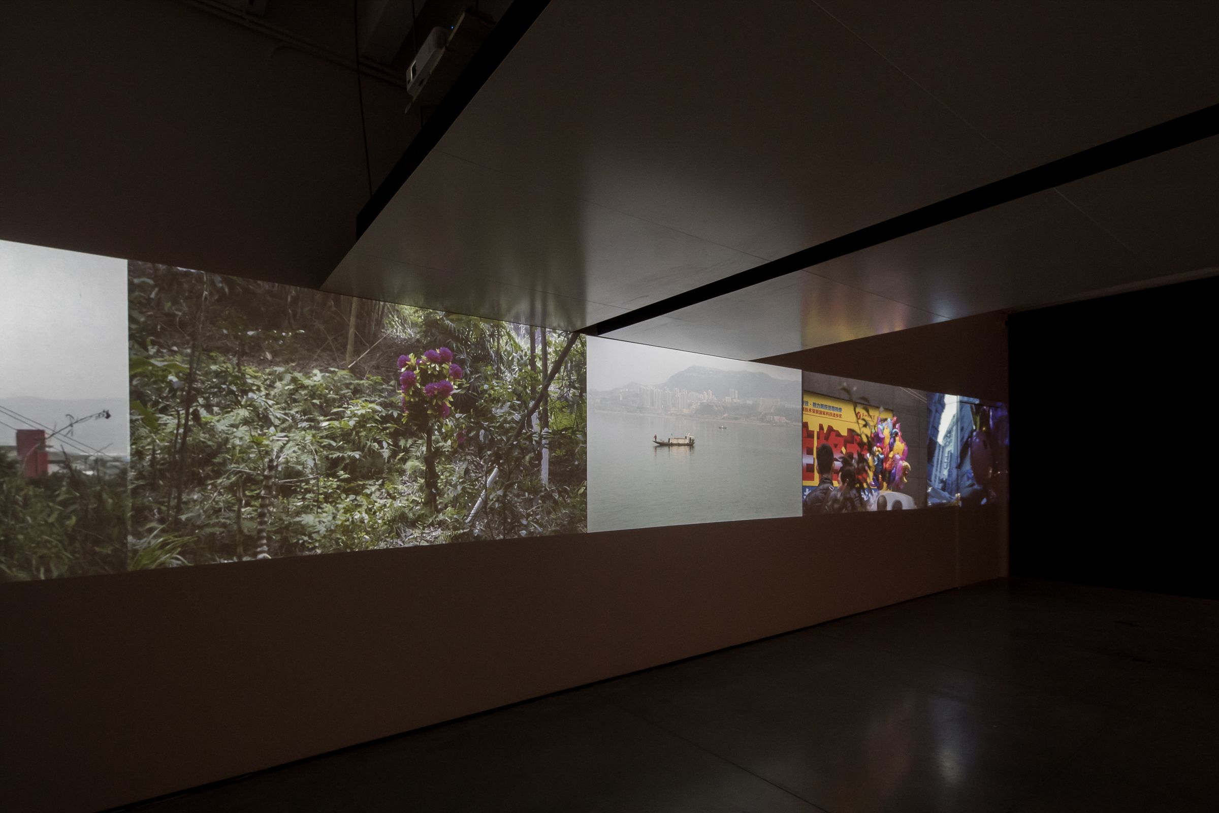 Dimly lit room with panoramic video projections on walls.