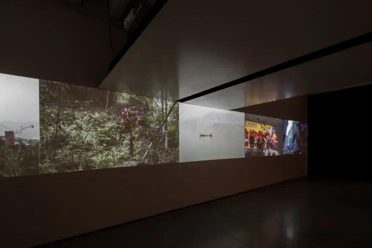 Dimly lit room with panoramic video projections on walls.