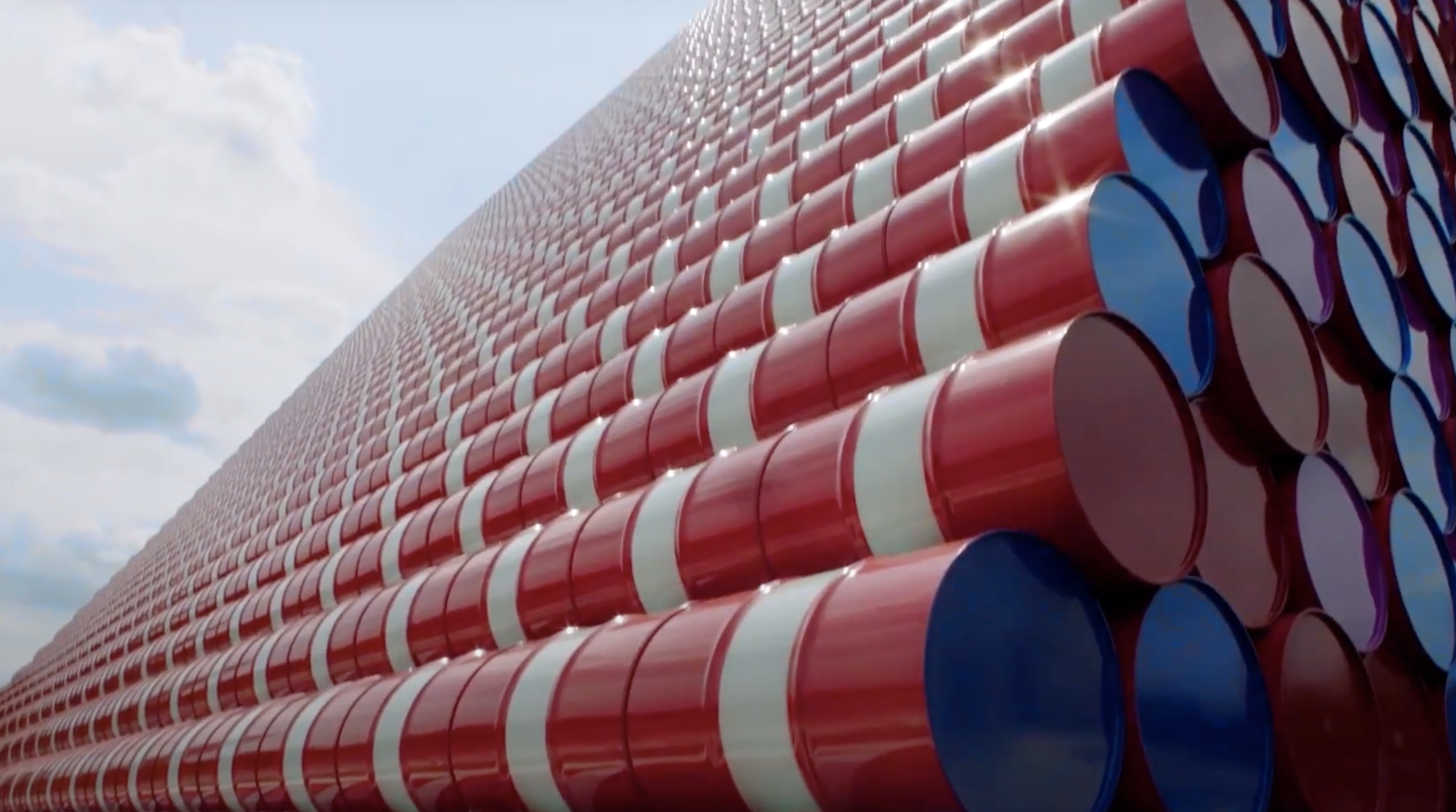 Stacked red and white barrels with colored bottoms form a pyramid. One side is in focus with the open sky visible in the b...