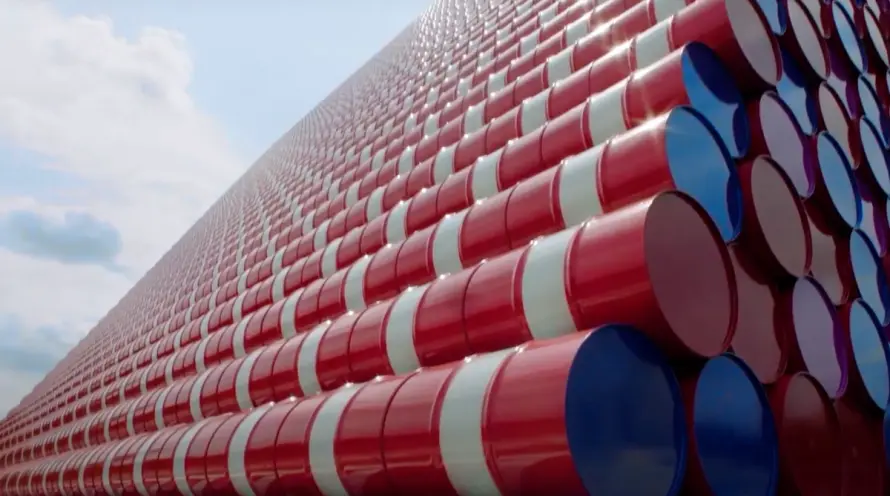 Stacked red and white barrels with colored bottoms form a pyramid. One side is in focus with the open sky visible in the b...