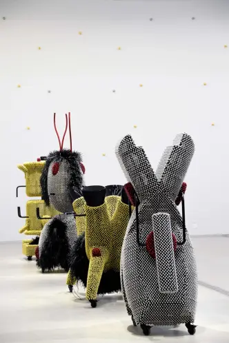 Installation artwork featuring structures adorned with metallic gold and silver pins, reminiscent of toys.
