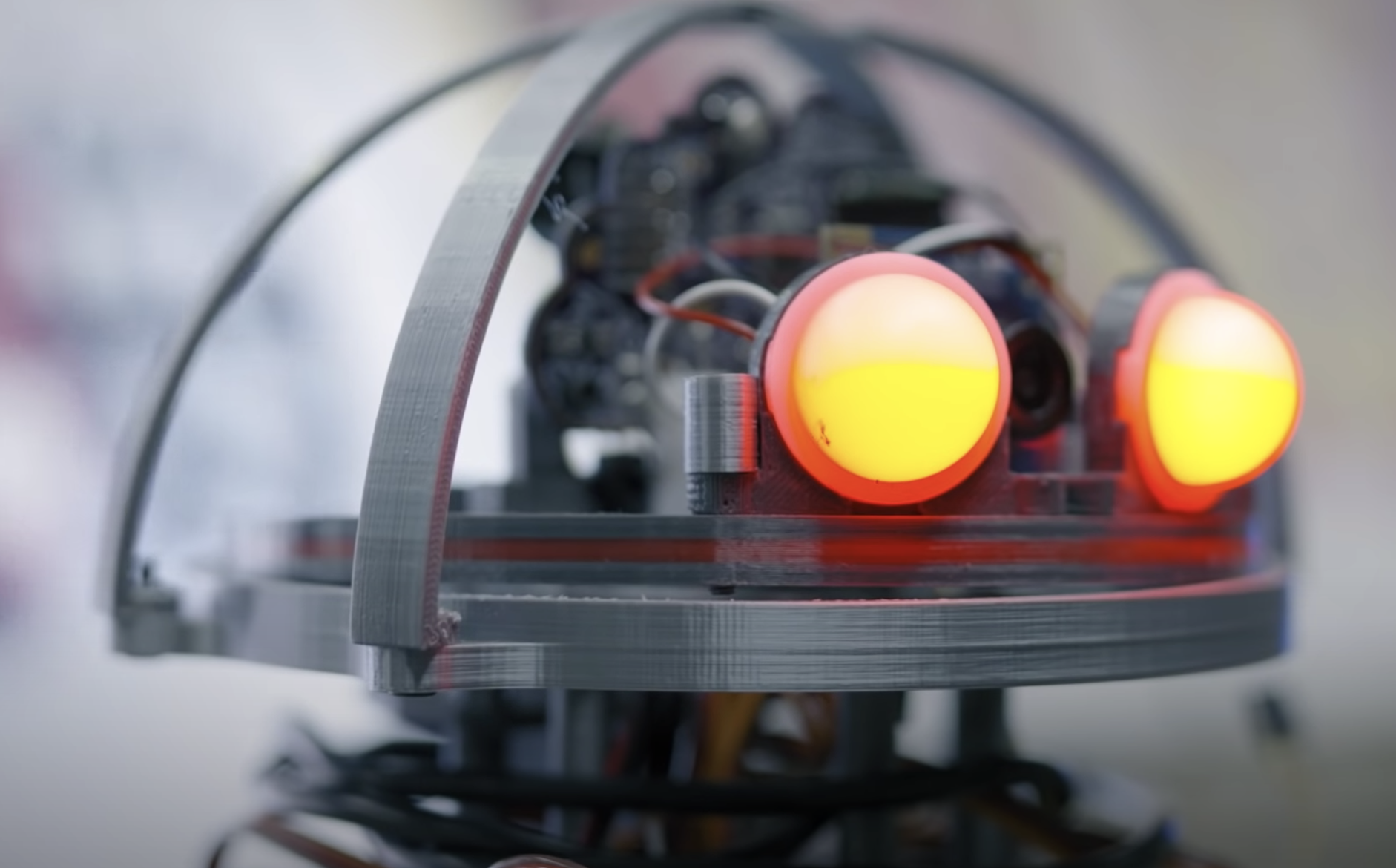 A close-up of a robot's head with glowing red lights functioning as eyes. The focus on the mechanical details of its face ...