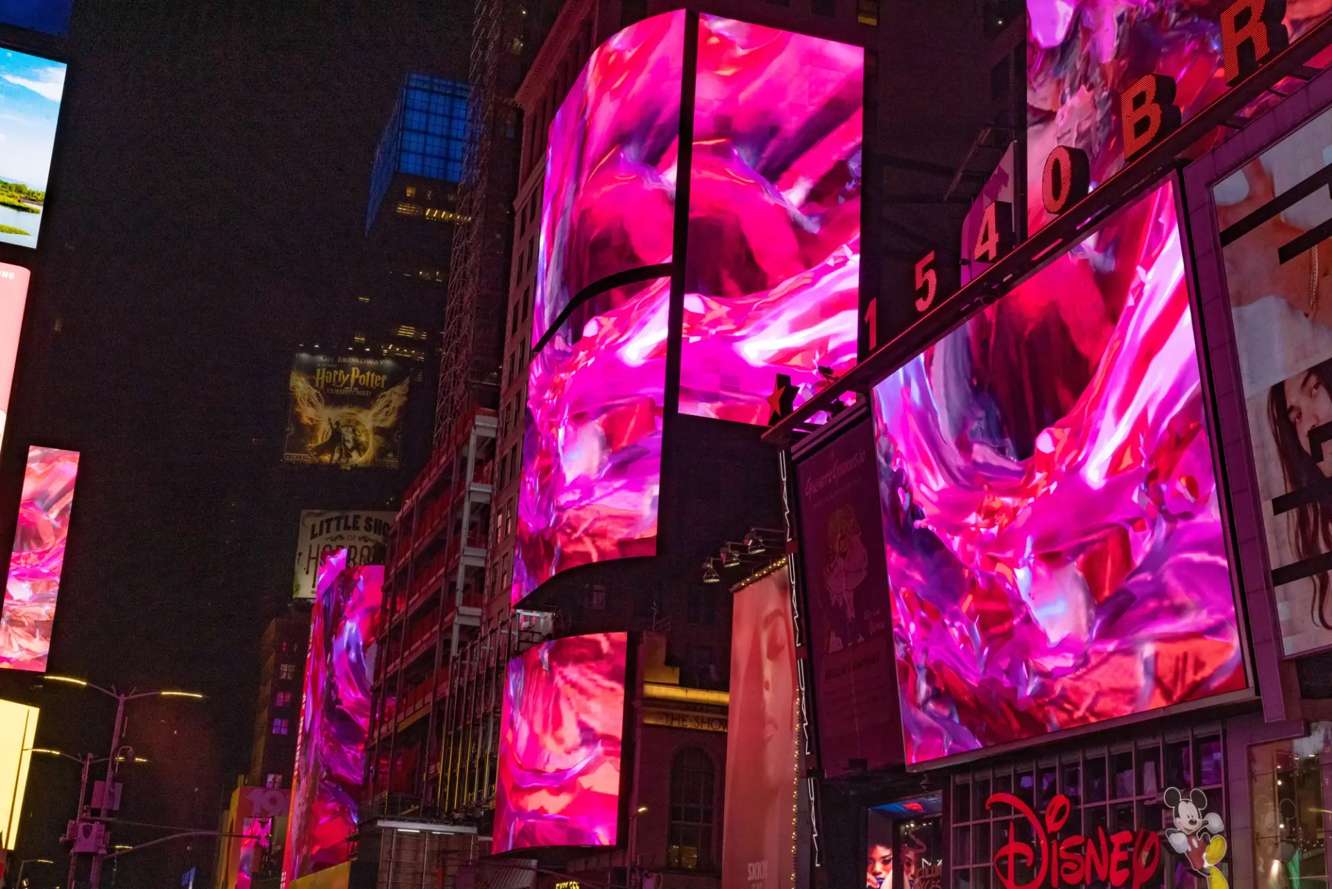 Abstract art depicted on massive building billboards, featuring swirls of pink tones, as part of Nancy Baker Cahill's 2022 Slipstream installation in Times Square.