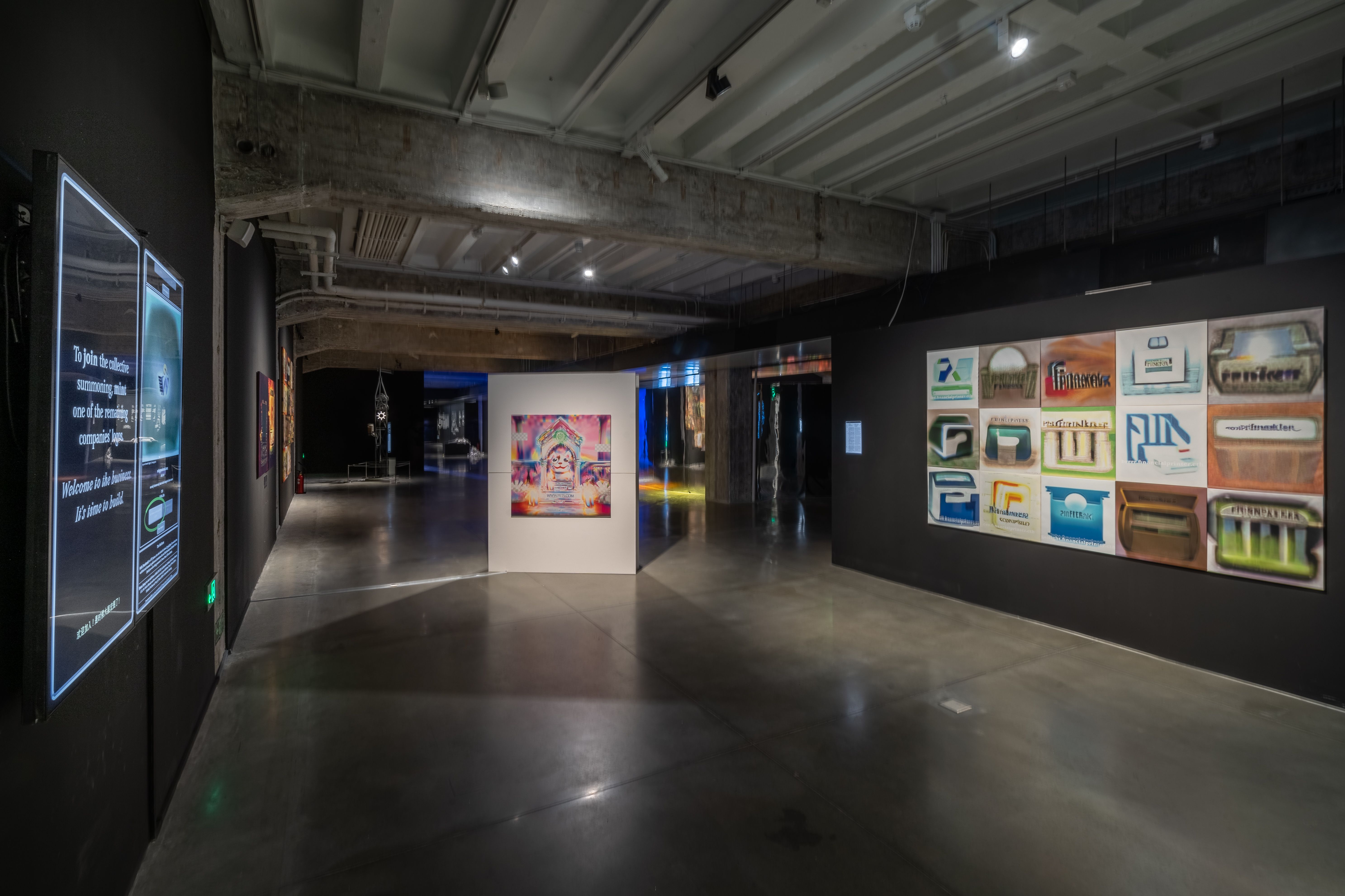 Long gallery shot with a digital informational display and vibrant wall art.