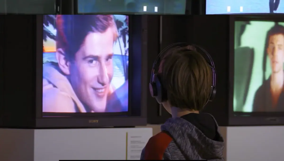 A child is gazing intently at a screen which is displaying vintage videos or images.