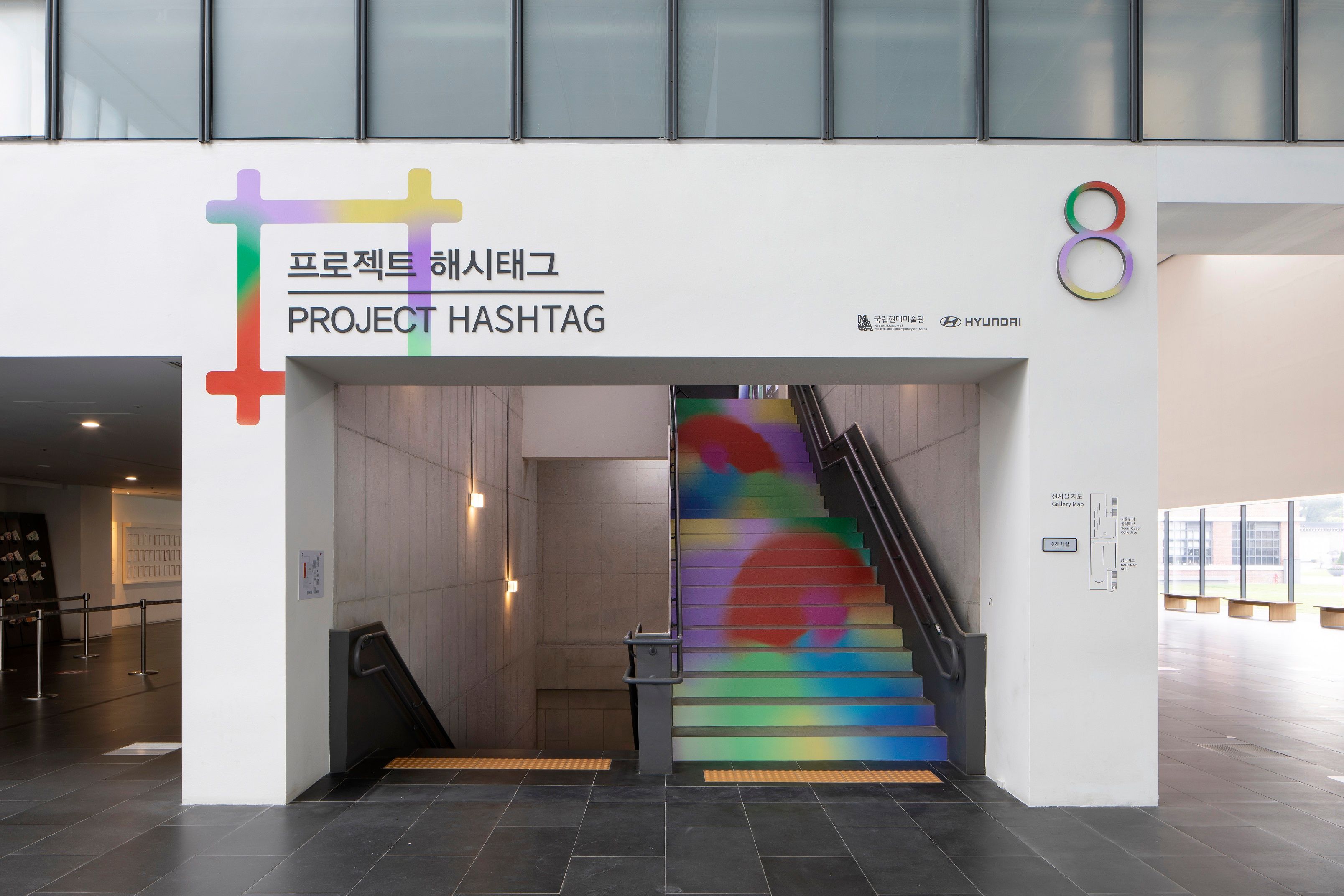A poster for PROJECT HASHTAG 2020 is prominently displayed in a metro station near the stairs.