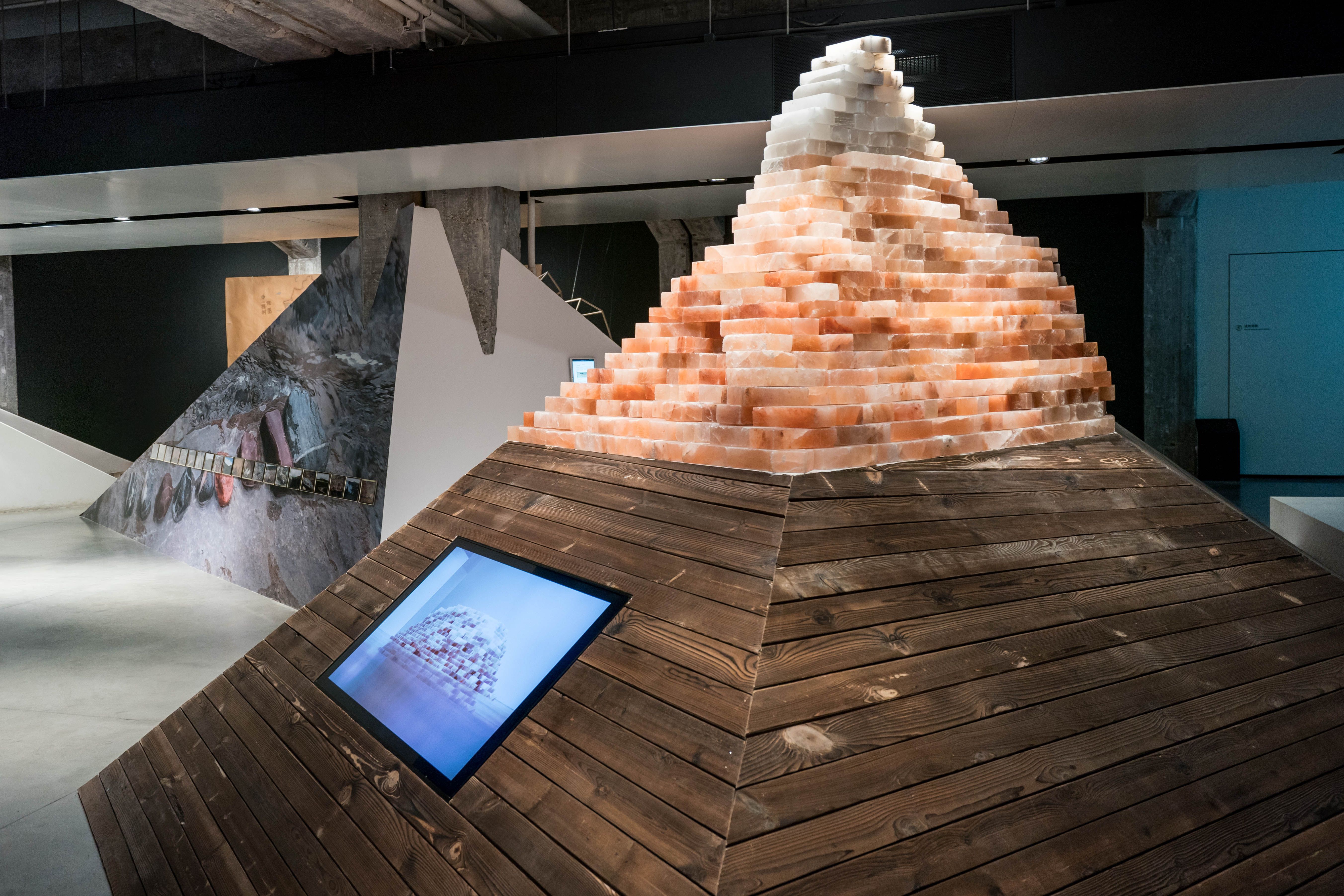 Salt brick pyramid with multimedia display on wooden ramp.