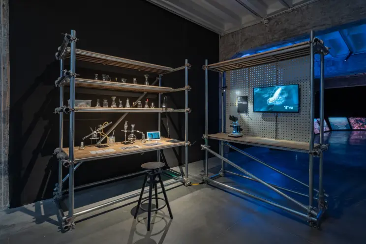 Industrial-style display shelves with various scientific objects and a screen.