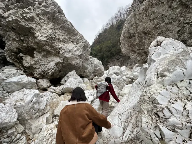 Two individuals are hiking on a trail through white rock mountains, engaged in an exploration of nature.