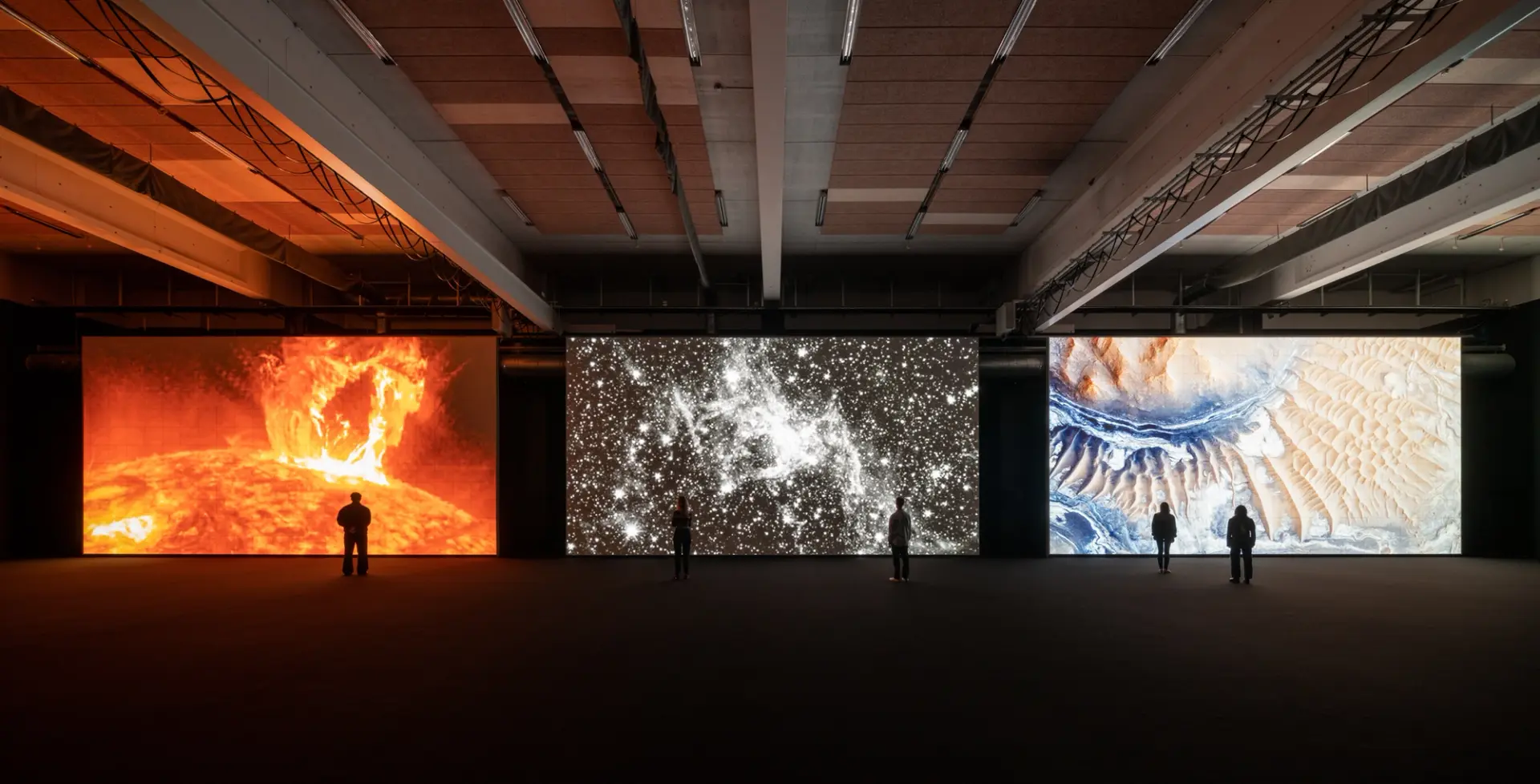 Three massive screens displaying astronomical art with people observing.