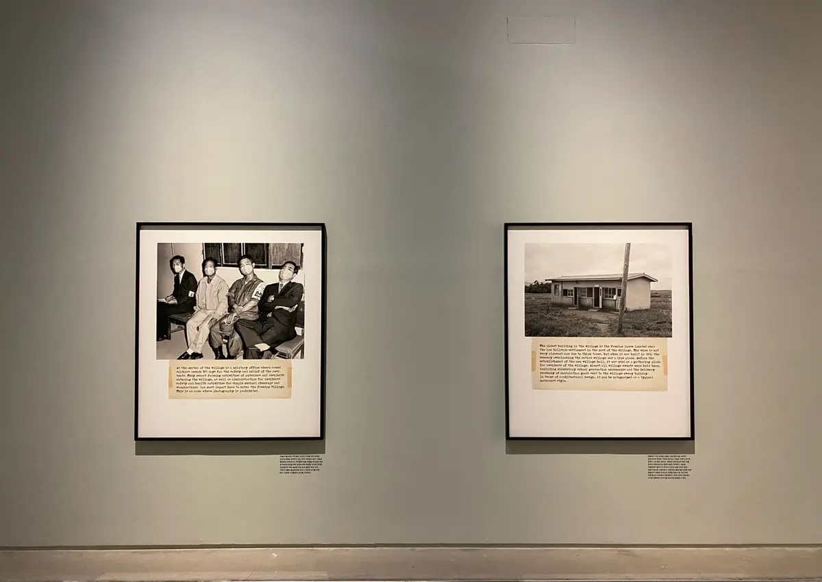 Two vintage photographs displayed in a gallery. One frame captures four individuals, while the other depicts a quaint building. 