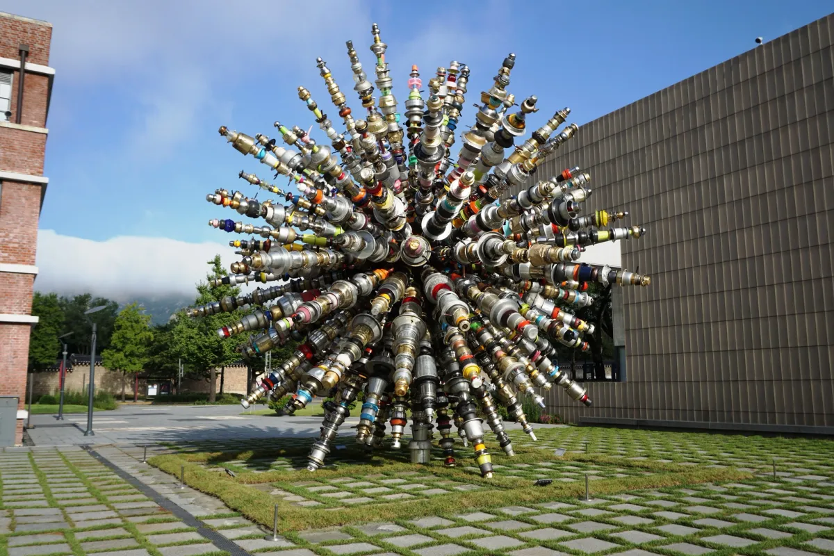A large outdoor sculpture with many elements protruding from the center, resembling a dandelion.