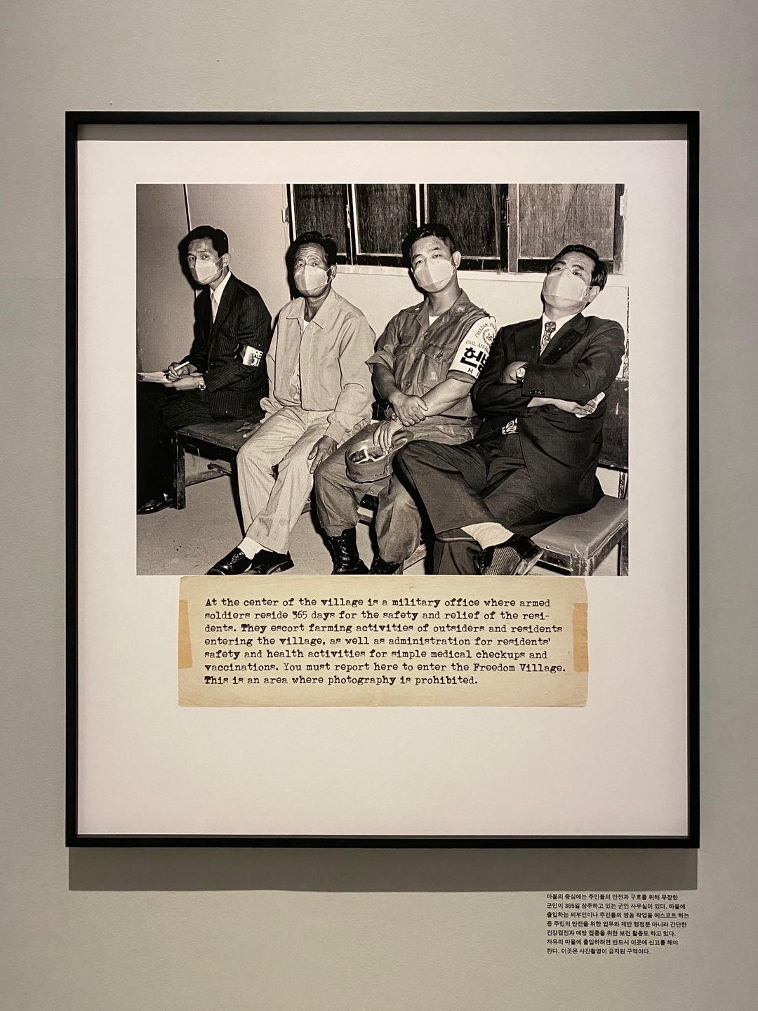 A framed digital print measuring 120x140cm is mounted on a wall, depicting four individuals with an accompanying caption a...