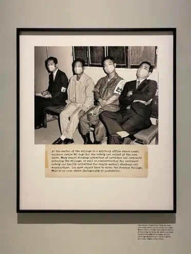 A framed digital print measuring 120x140cm is mounted on a wall, depicting four individuals with an accompanying caption a...