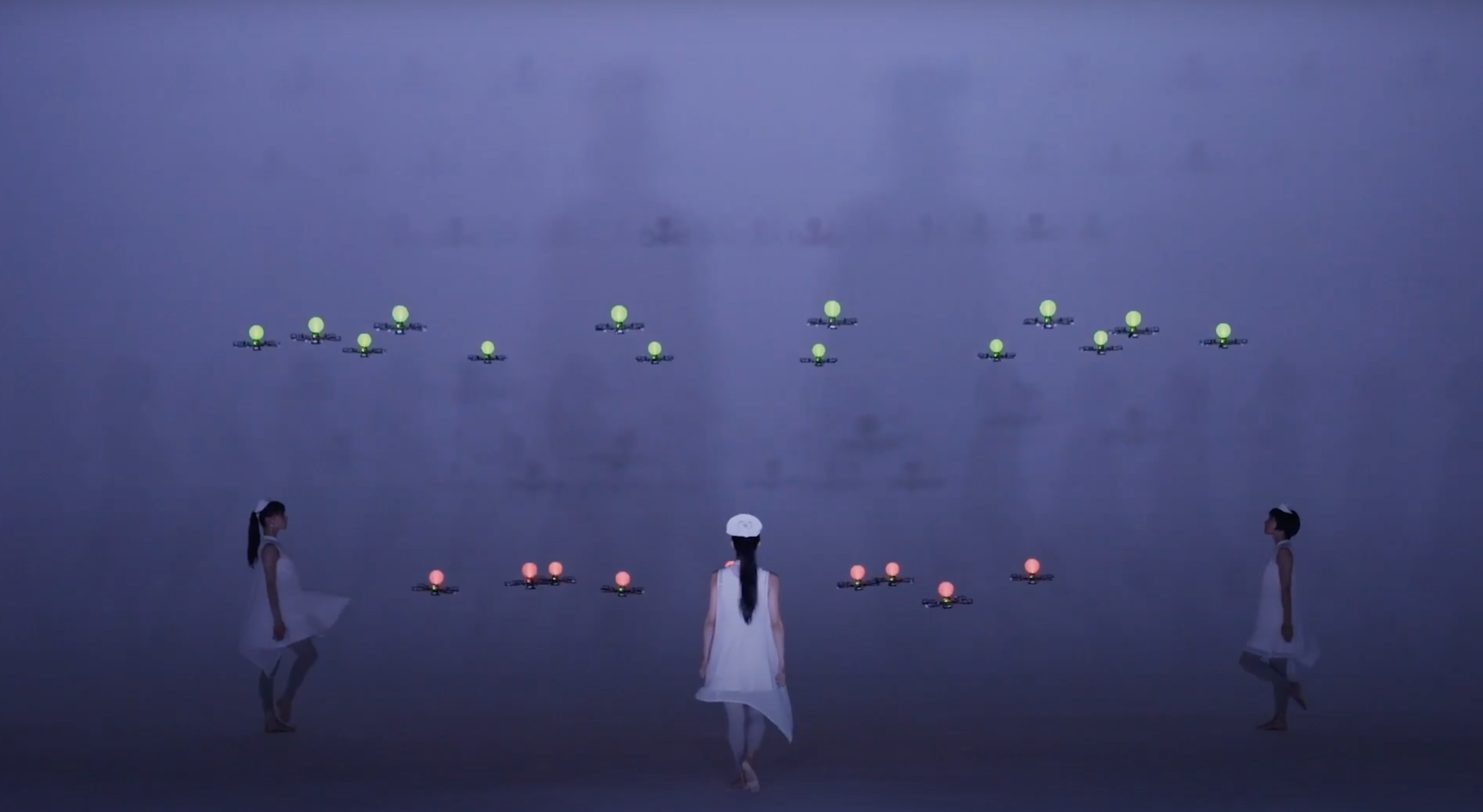 Three people in white attire stand in a triangular arrangement, each surrounded by devices that resemble drones glowing wi...