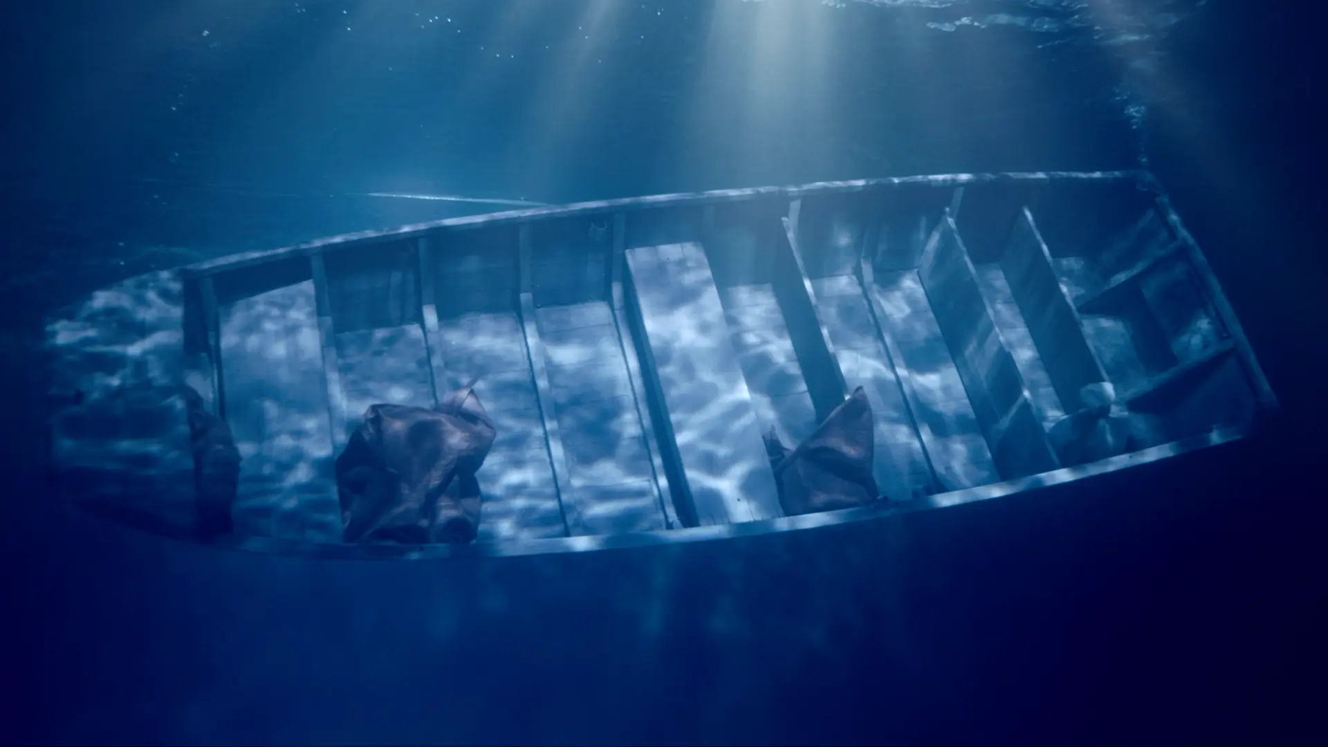 An underwater photograph showing a rowboat sinking to the ocean floor, with sun flares penetrating from above the water su...
