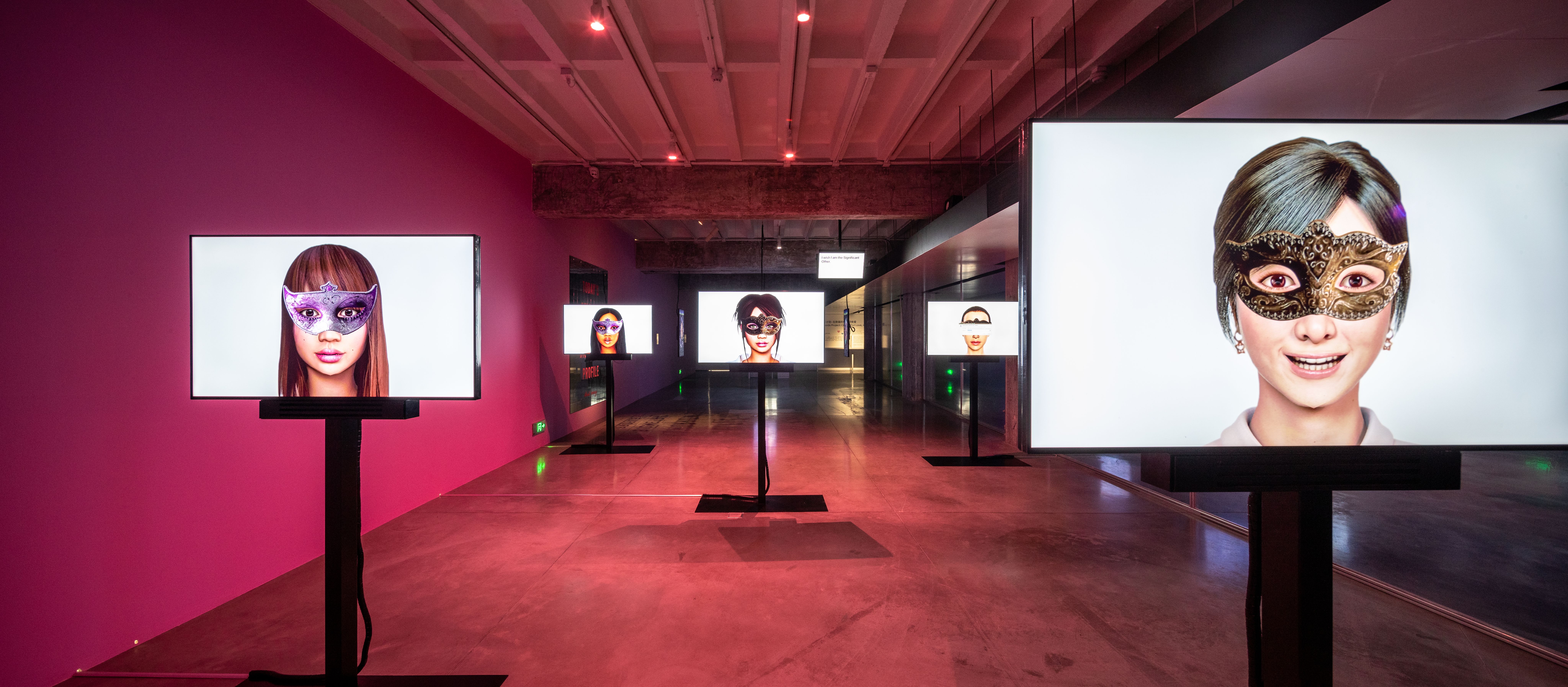 An art exhibit with monitors displaying faces in masks.