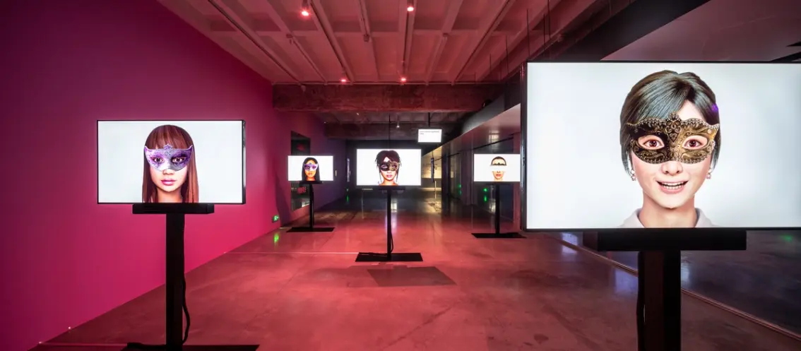 An art exhibit with monitors displaying faces in masks.