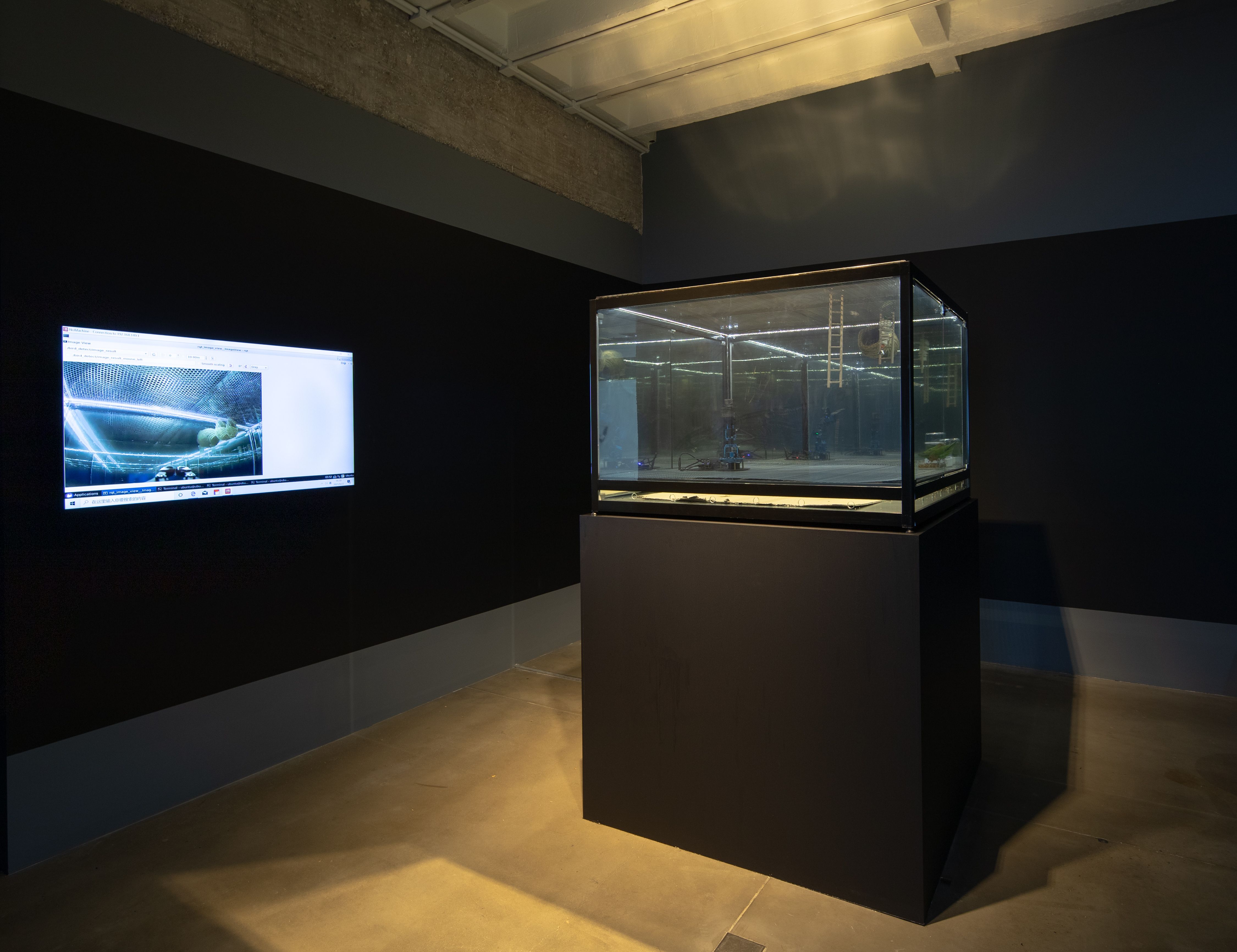 A black display case with screens showing car images in a dark room.