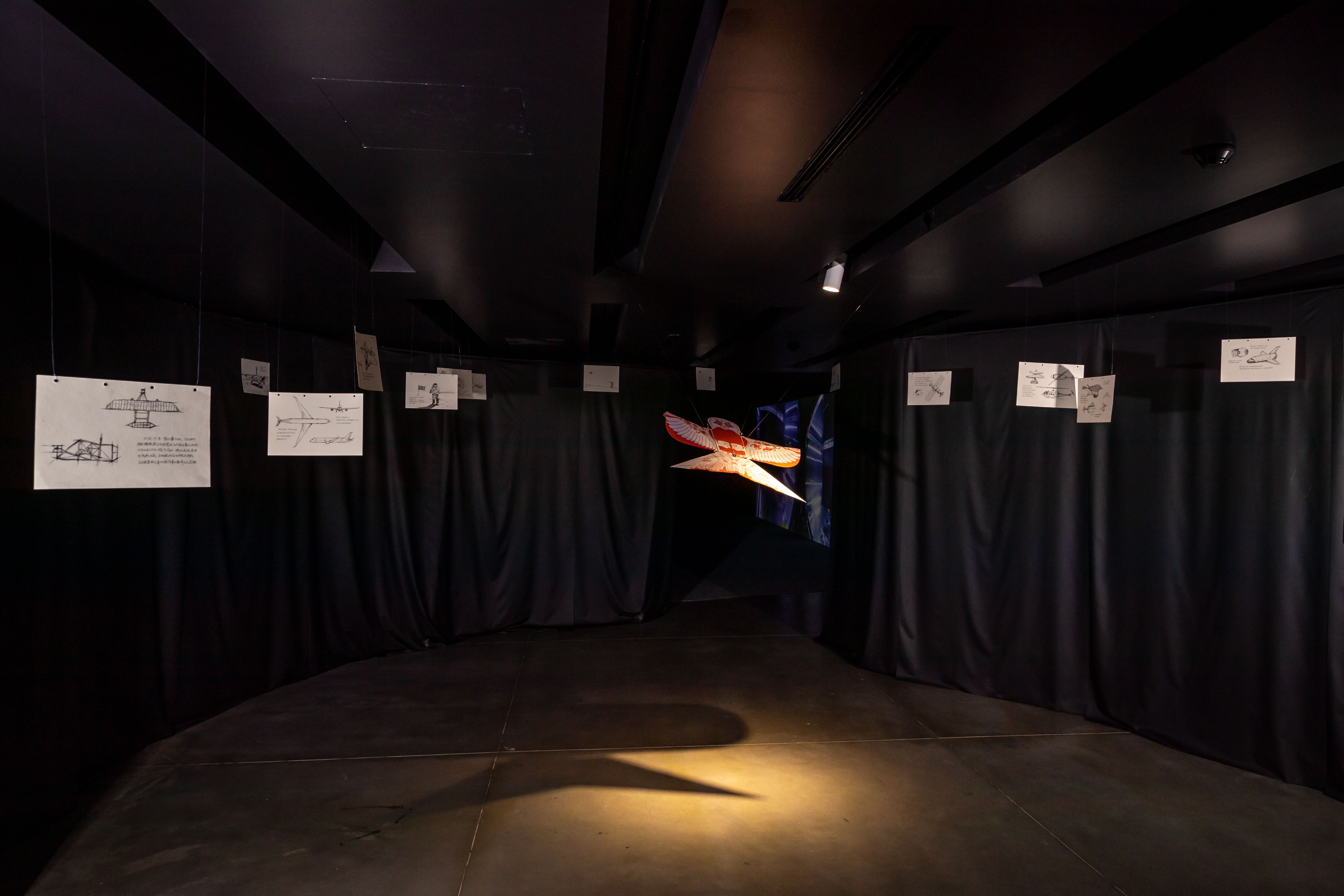 Dark gallery with spacecraft model and drawings of aerospace concepts.