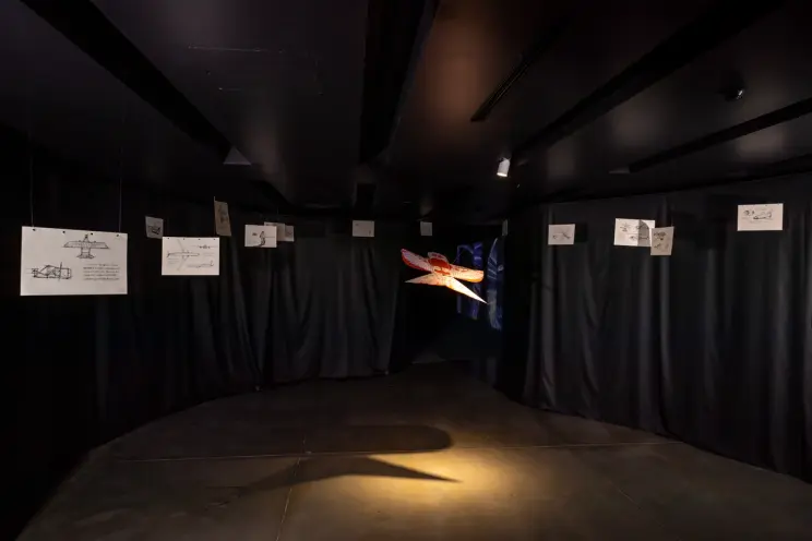 Dark gallery with spacecraft model and drawings of aerospace concepts.