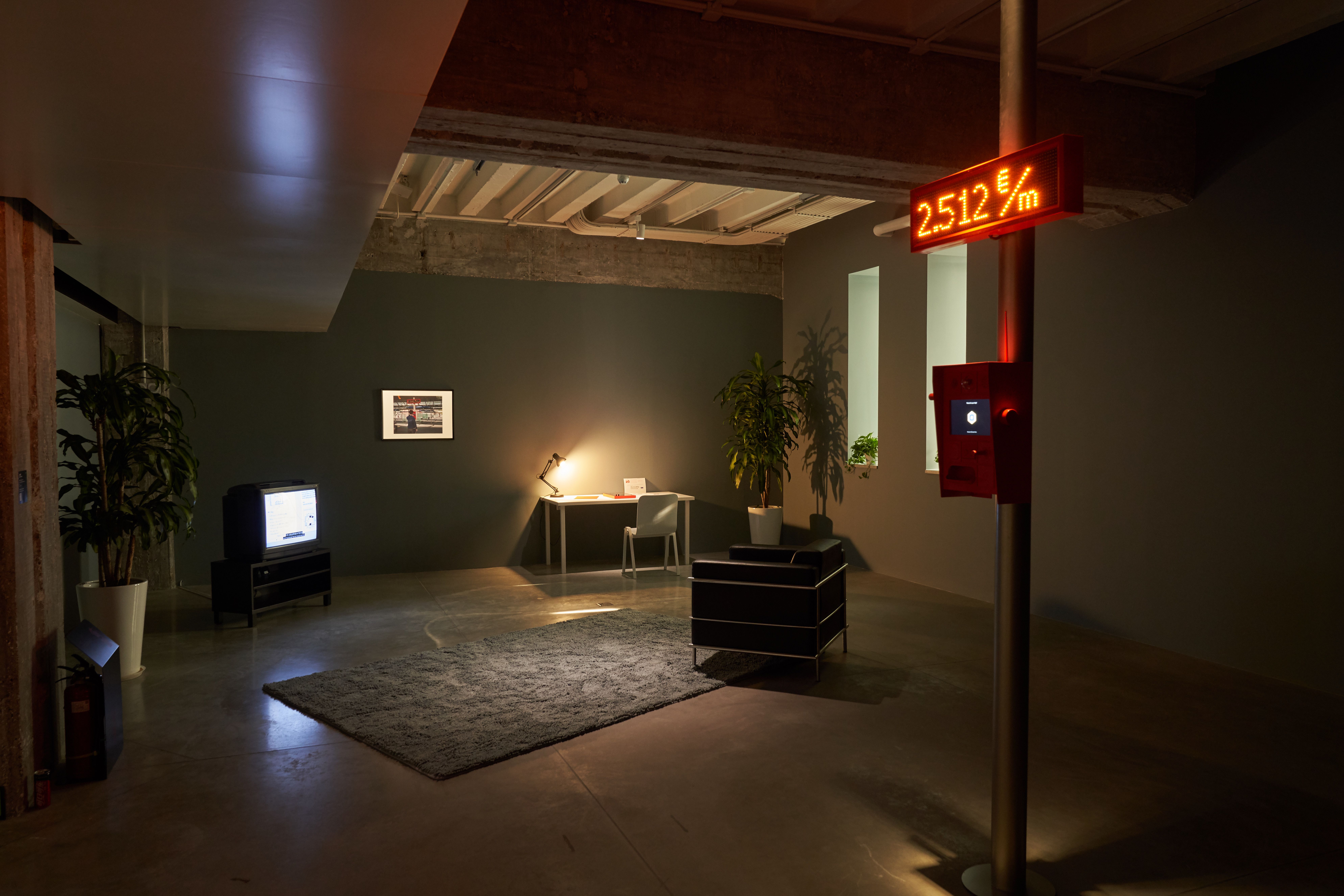 Office setup in dark room with red numerical display.