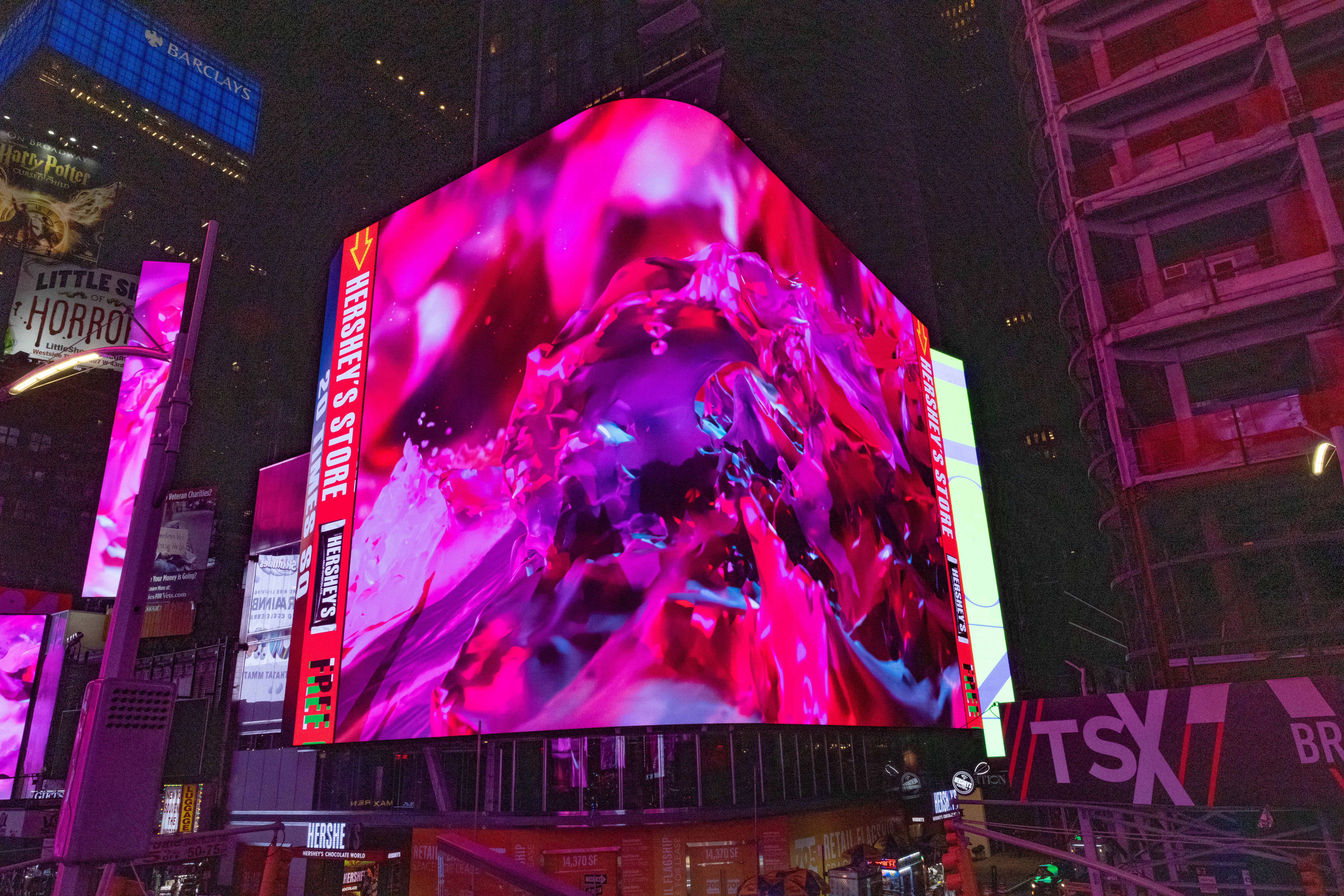 A corner building billboard in Times Square showcases a video of abstract art by Nancy Baker Cahill, 2022.
